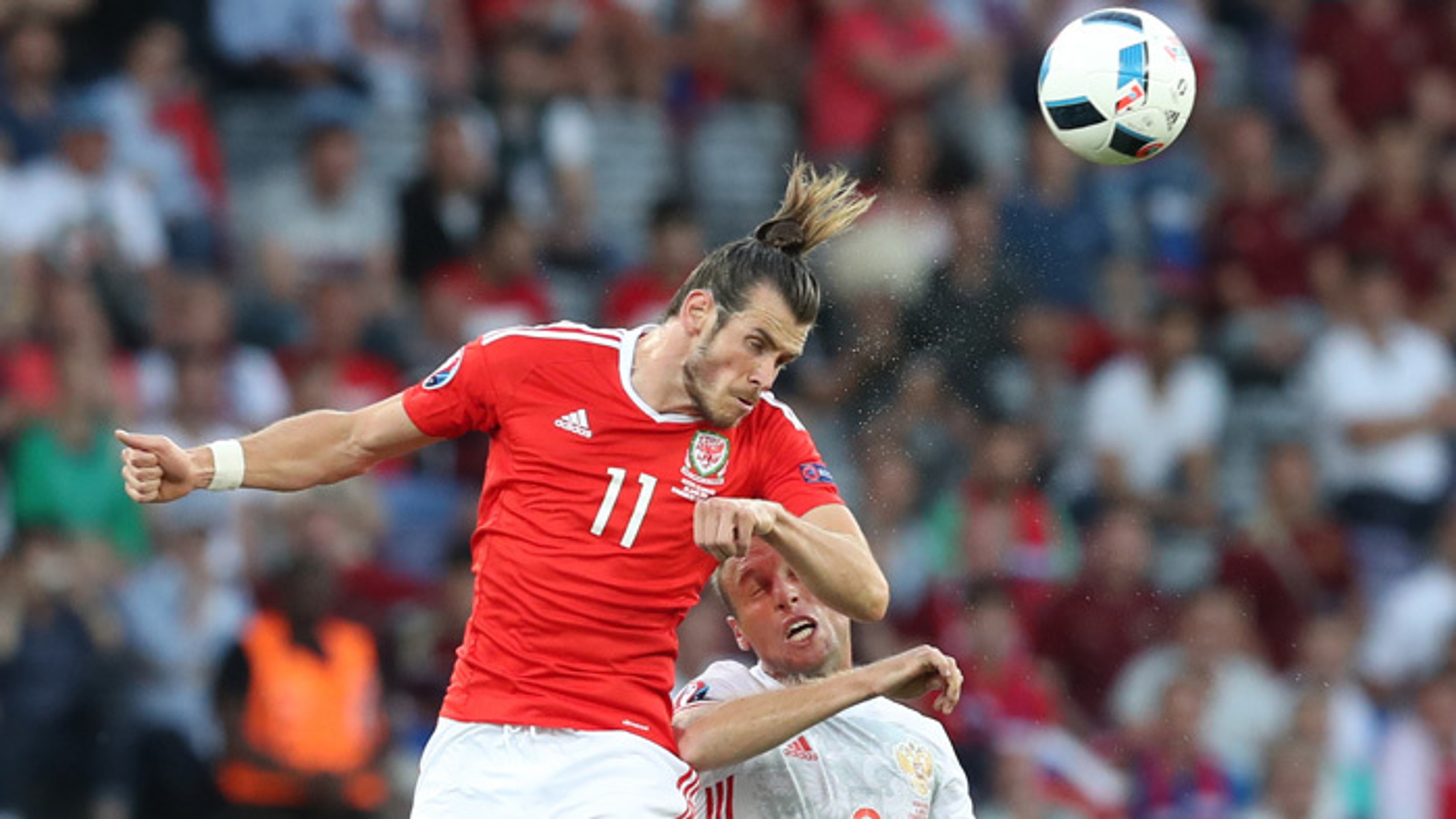 Walesan Gareth Bale hlavičkuje loptu v súboji s ruským hráčom Denisom Glušakovom.