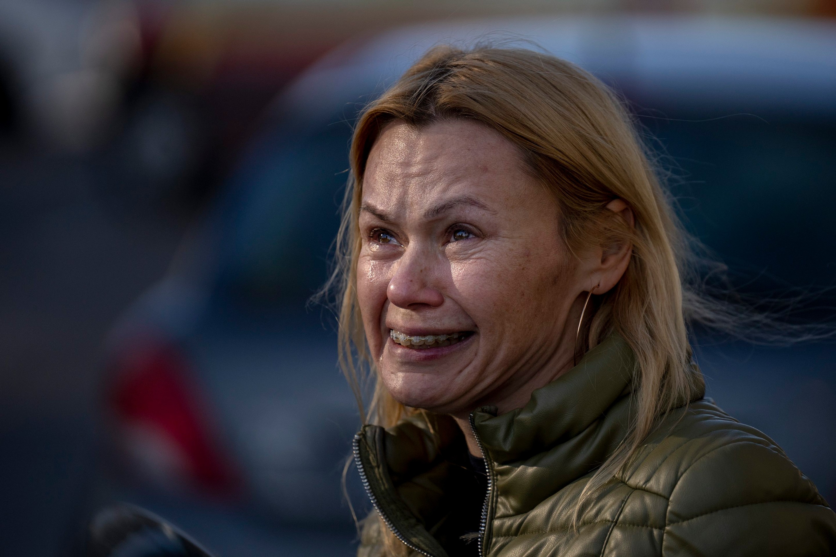 Žena plače, keď sa pozerá na zničený bytový dom po raketovom útoku
