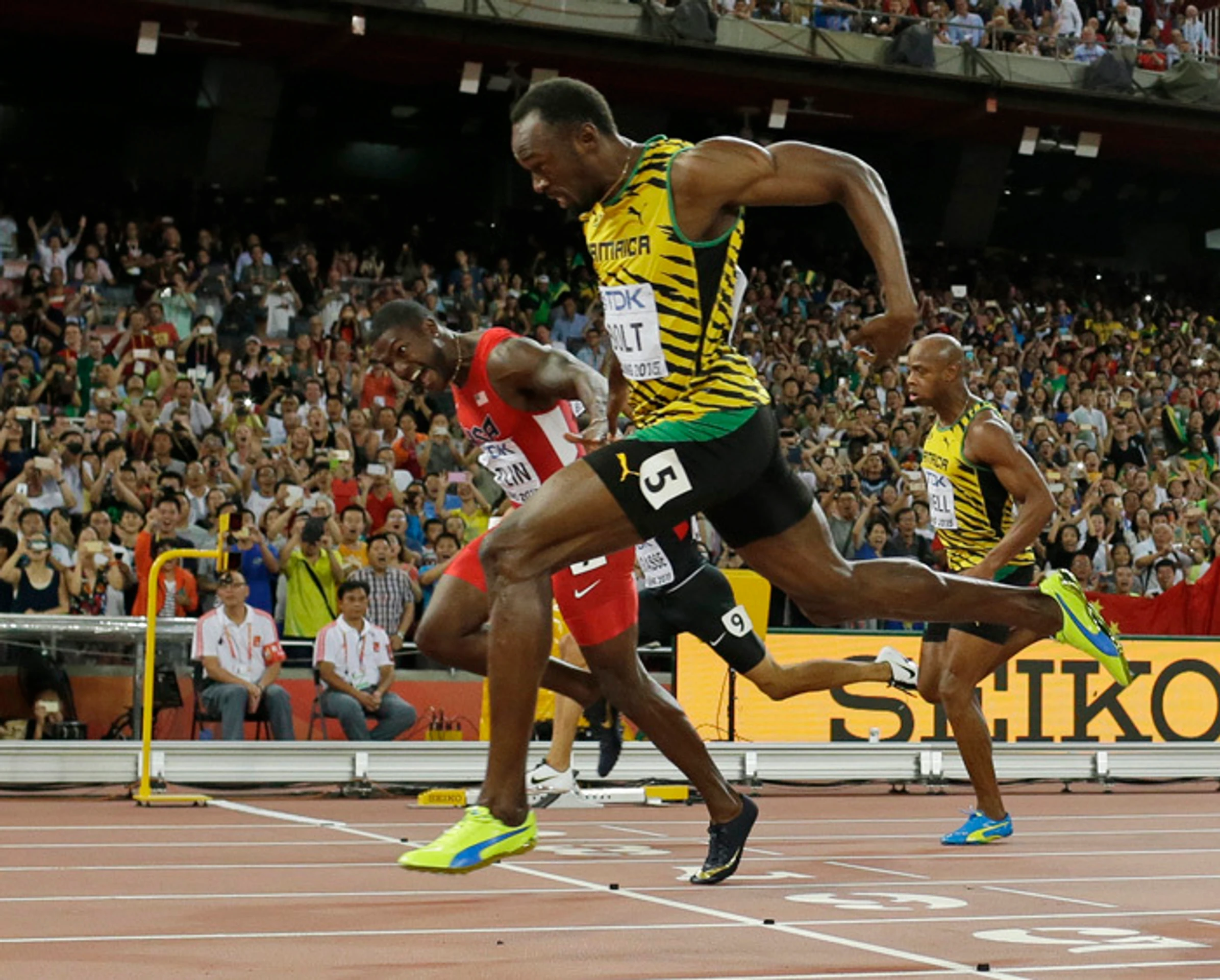 Usain Bolt víťazi vo finále na 100 m na MS v atletike o sekundu pred Justinom Gatlinom (USA) v červenom drese.