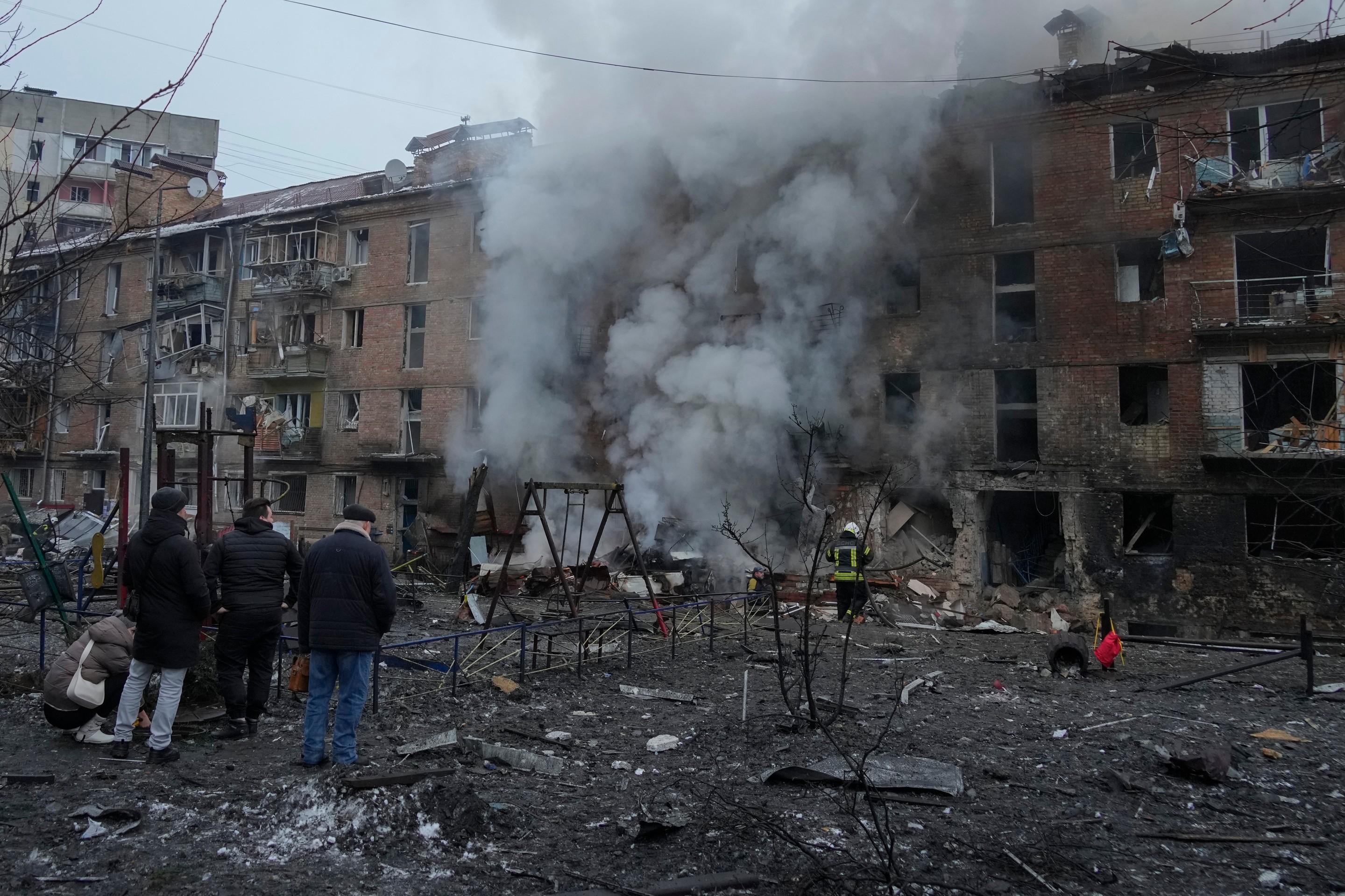 Ľudia si prezerajú materiálne škody na obytnej budove po ruskom raketovom útoku v Kyjeve.