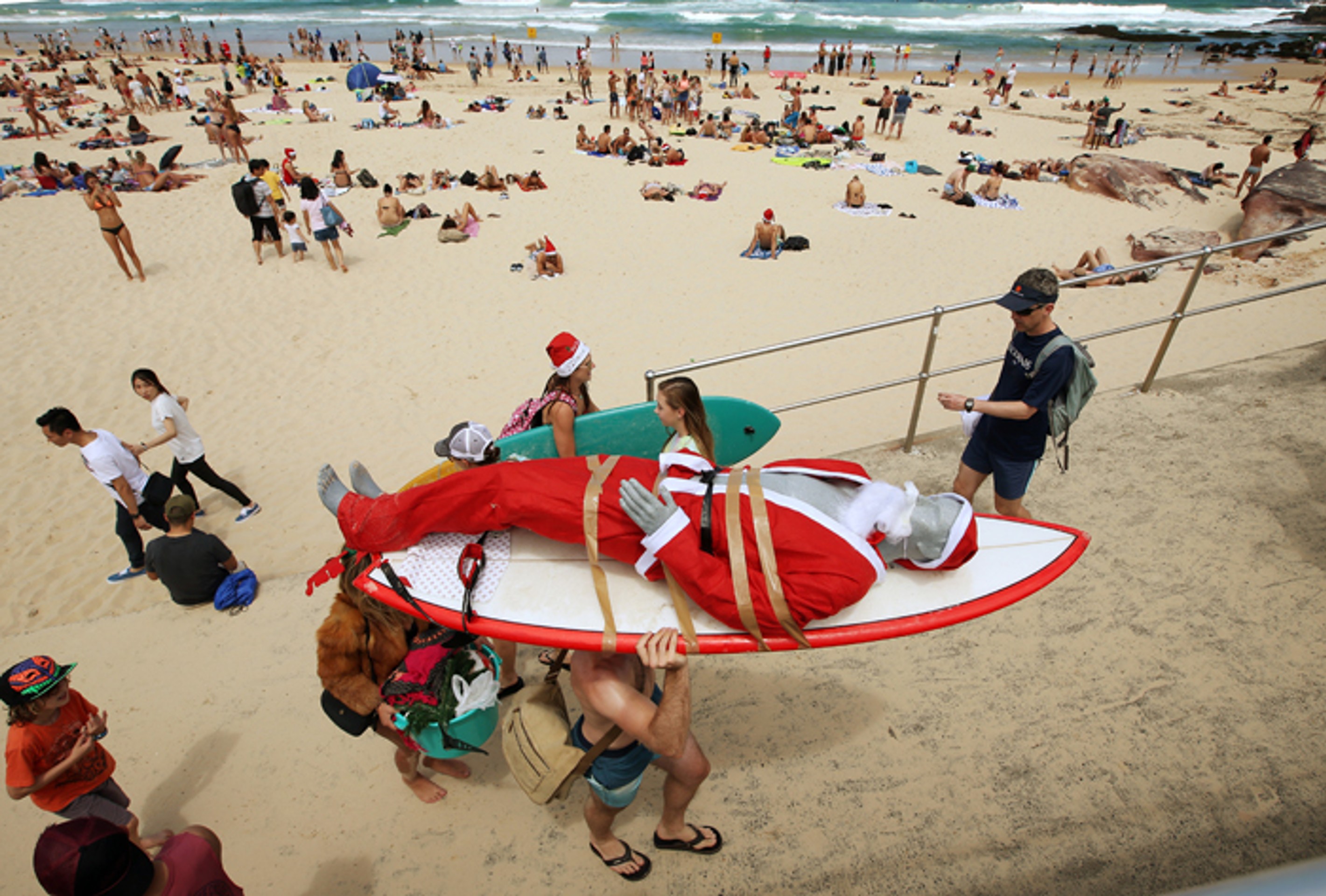 Figurína Santa Clausa je pripevnená na surfe, aby ju ľahšie prepravili po pláži Bondi Beach v Austrálii.