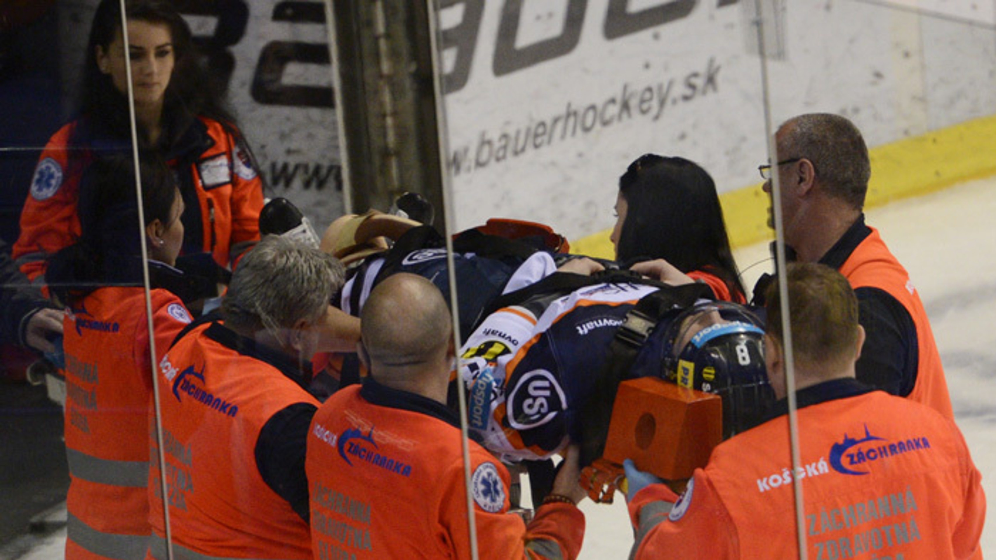 Záchranári odnášajú na nosidlách z ľadovej plochy zraneného hokejistu Košíc Branislava Pavúka.