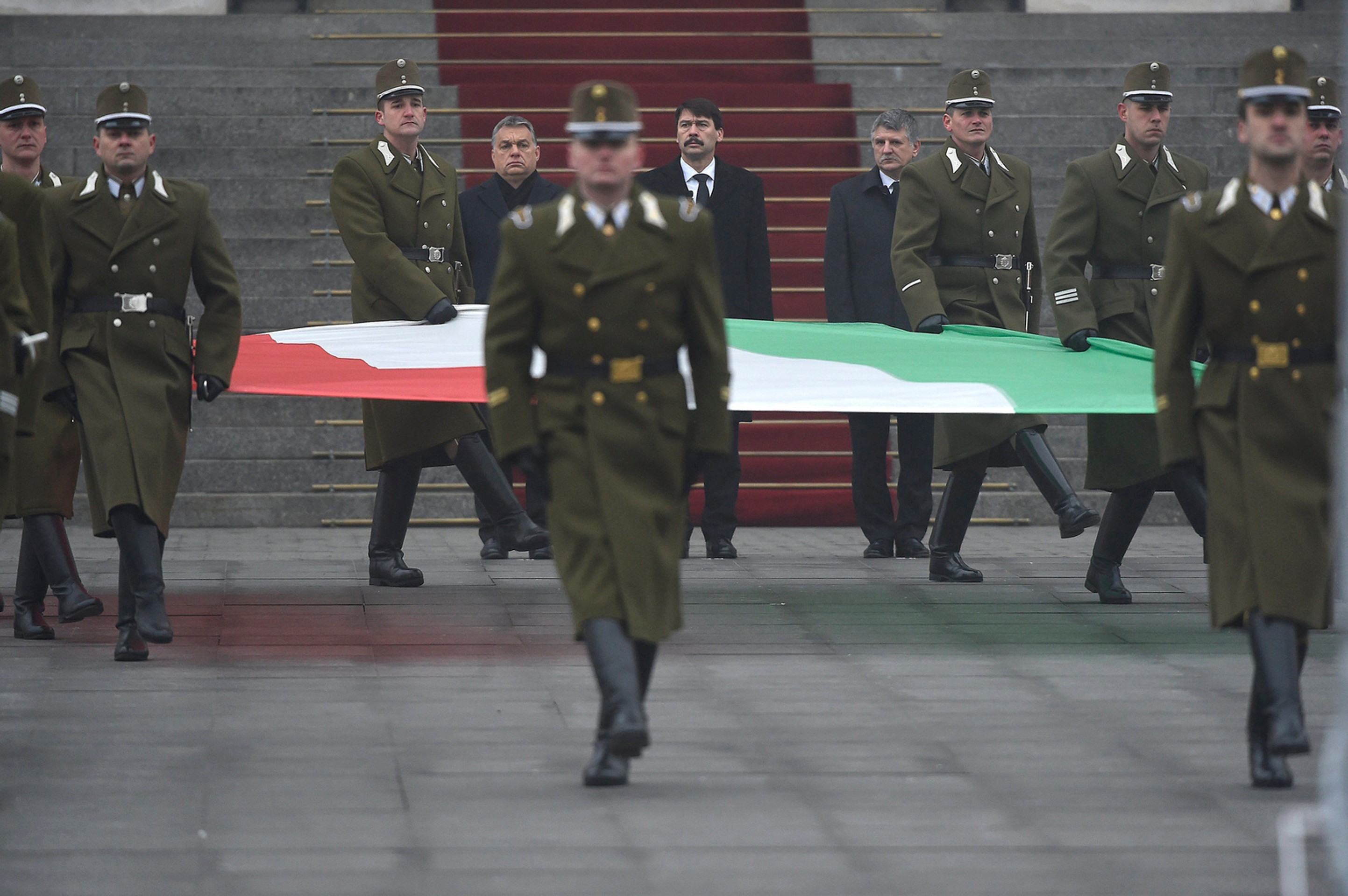 Maďarský premiér Viktor Orbán, maďarský prezident János Áder a predseda parlamentu László Kövér kráčajú pred vojakmi, ktorí nesú