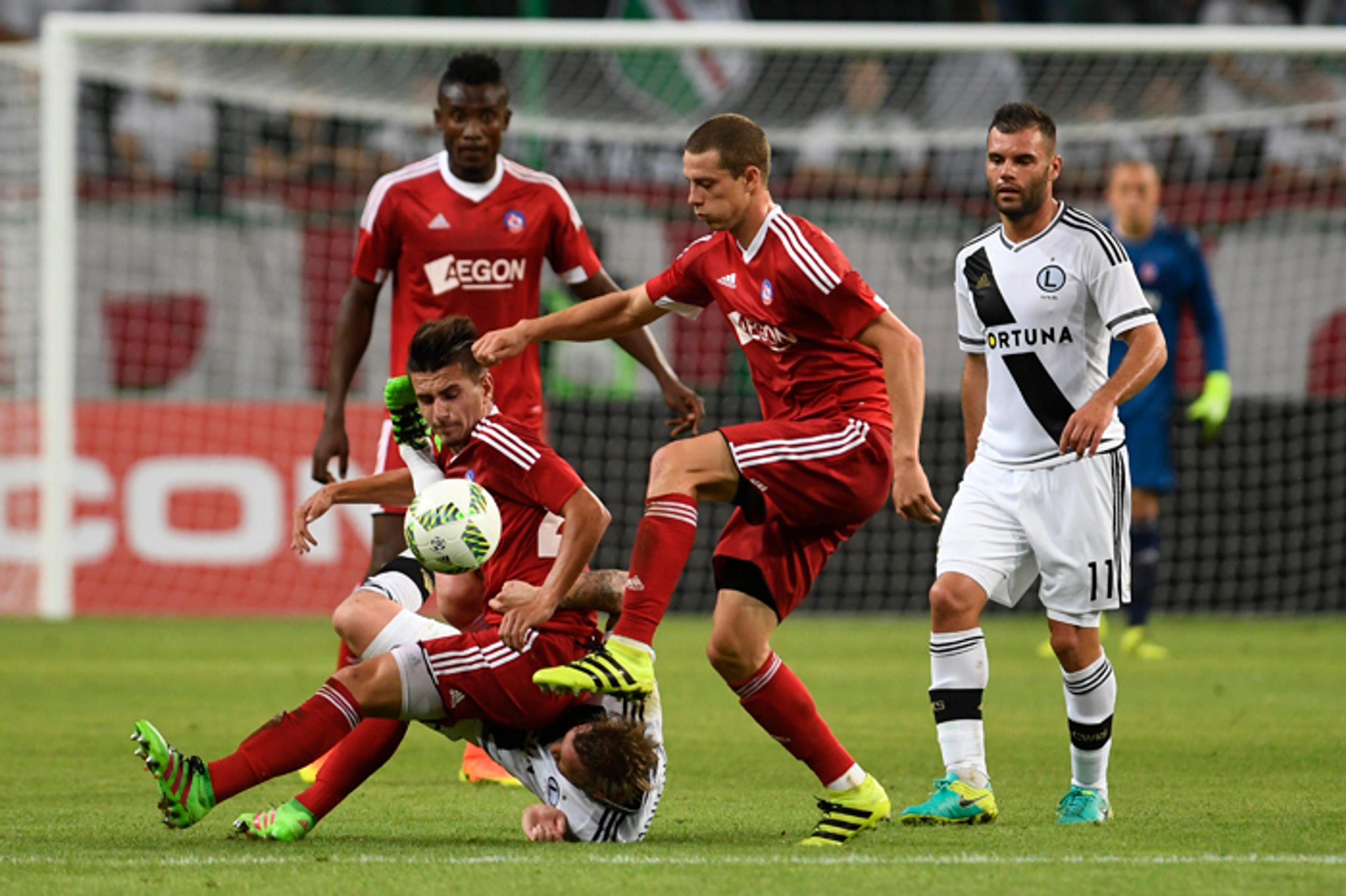 Trenčania Denis Jančo (dole), Christopher Udeh (vľavo vzadu), James Lawrence (druhý sprava) a hráči Varšavy Nemanja Nikolič (vpr