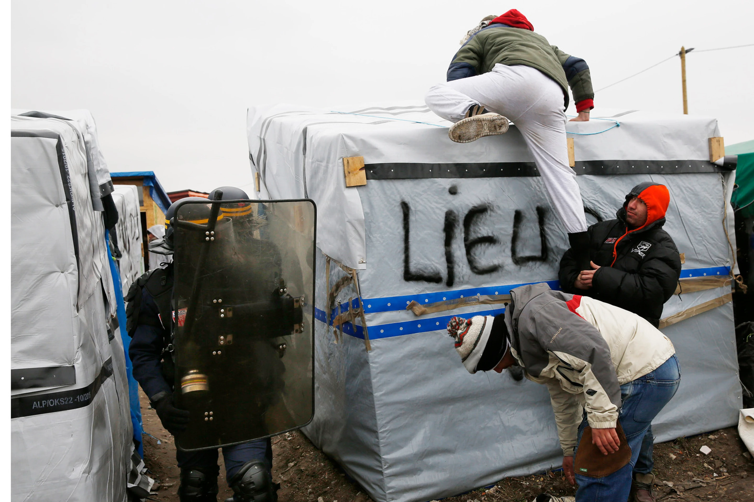 Migranti v tábore pri Calais protestujú na strechách búd.