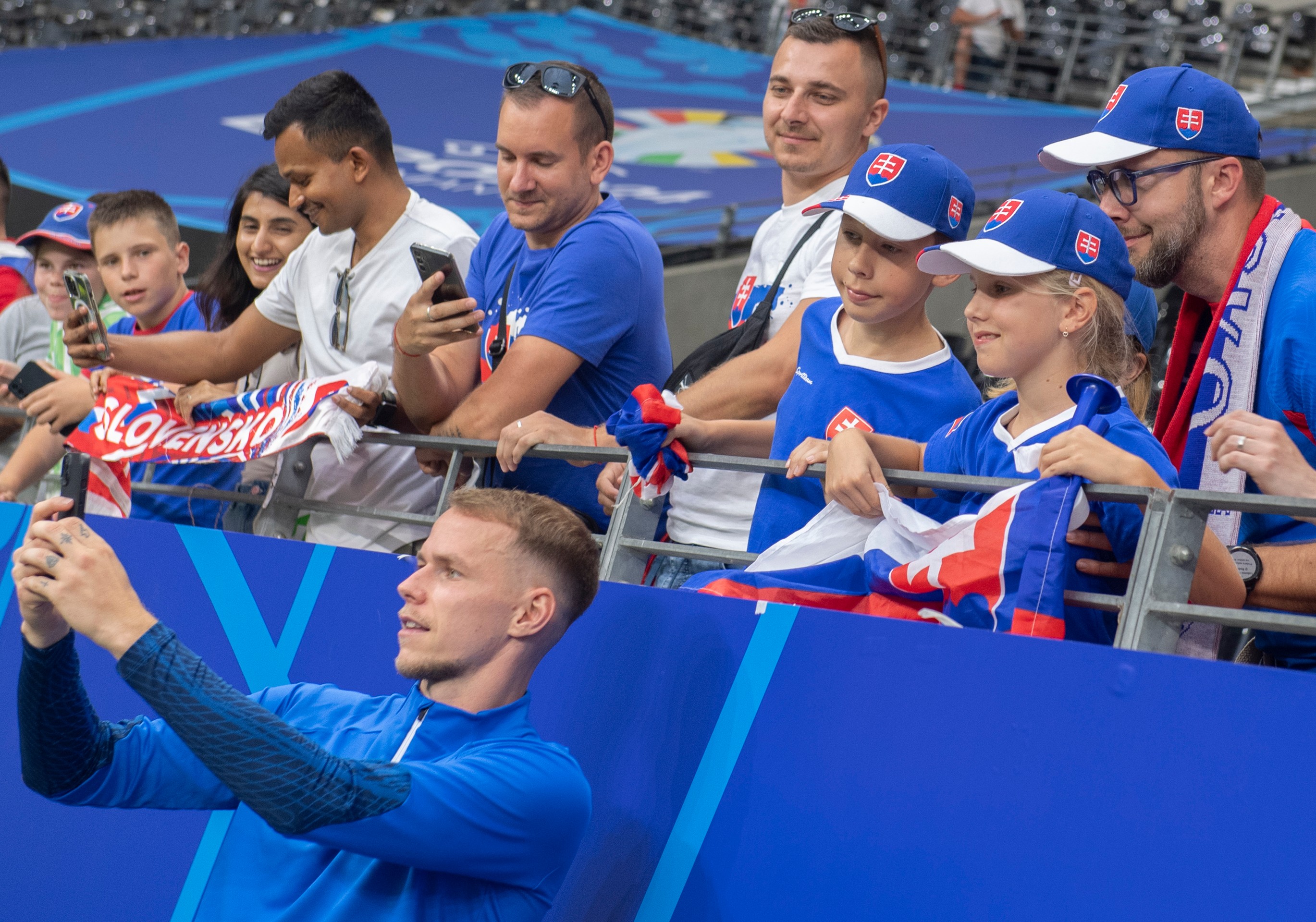 Ondrej Duda (dole) sa fotí s fanúšikmi po zápase s Rumunskom na ME 2024.