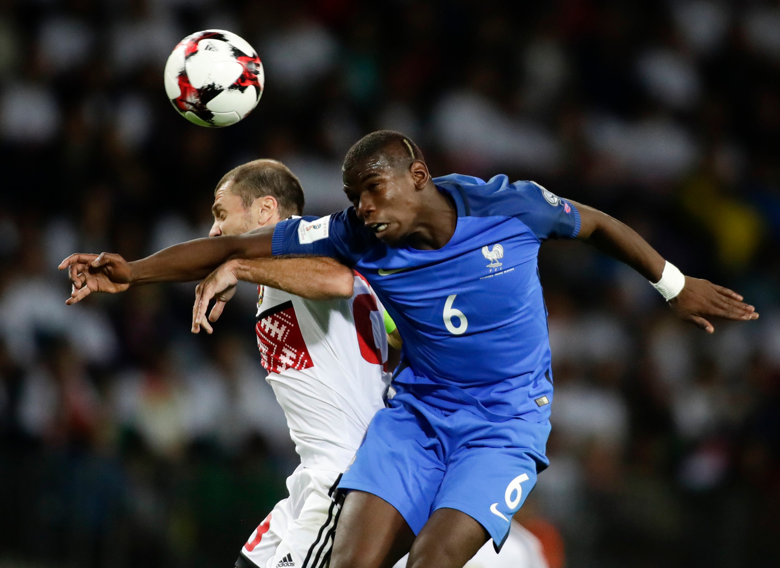 Megahviezda Francúzska Paul Pogba (v modrom) hlavičkuje pred bieloruským Ivanom Majevskim v kvalifikácii MS 2018.