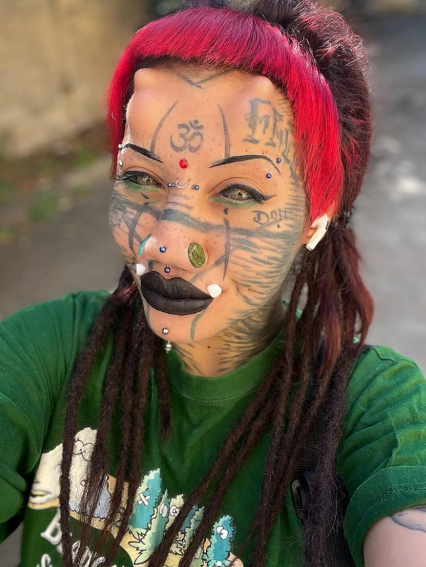 Tvár má plnú piercingov a tetovaní