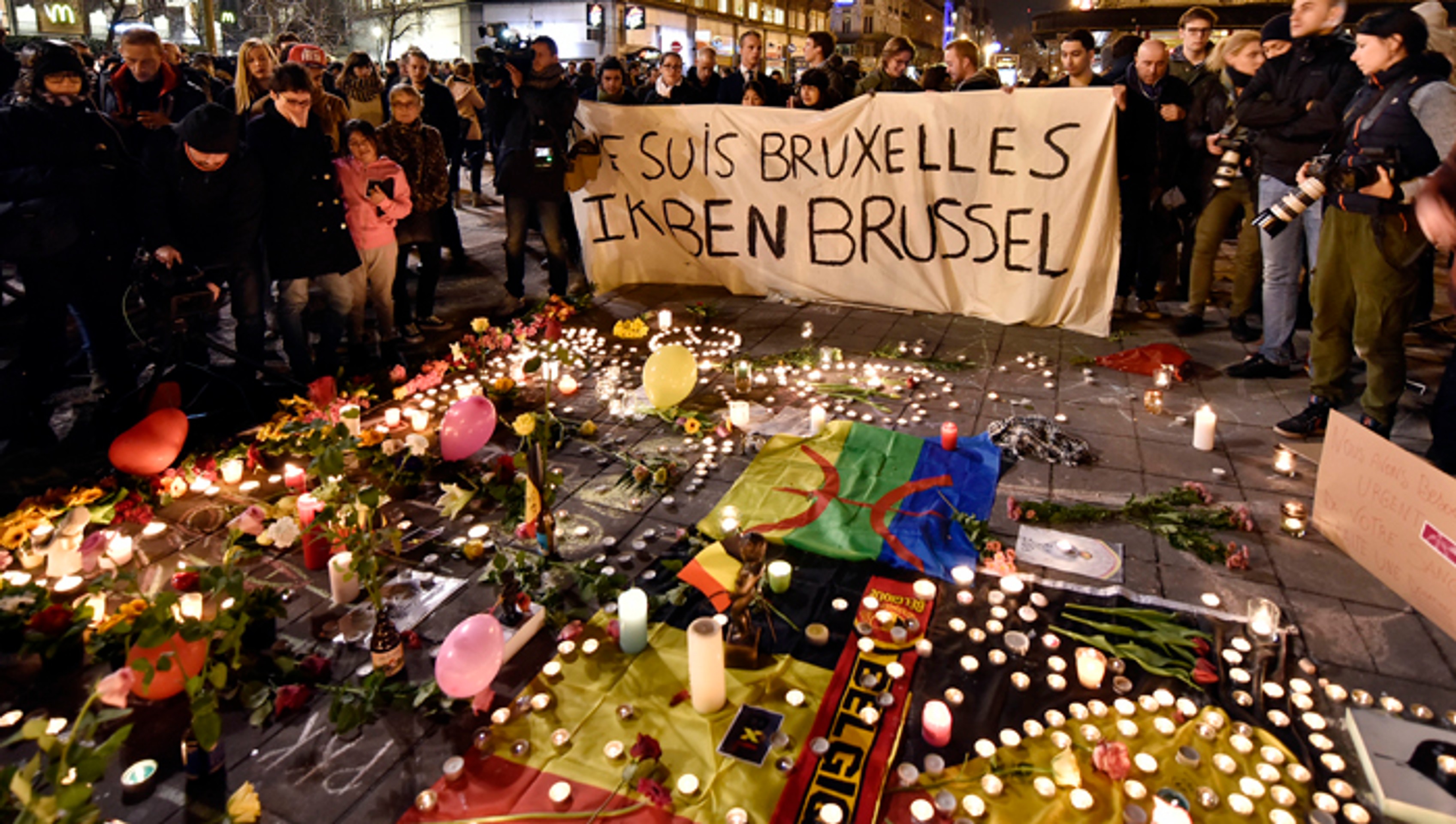 Na snímke ľudia držia transparent vedľa kvetov a sviečok na pamiatku obetí teroristických útokov v centre belgickej metropoly.